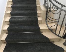 Luxury grey carpet installed on stairs with stair rods